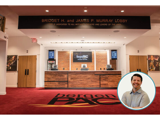 The main lobby of the iconic Bergen Performing Arts Center is a vibrant space that patrons want to spend time in. Pictured in the lobby are industrial design elements, such as wooden panels, juxtaposed to traditional elements, such as ornate gold railings. Also pictured is the author’s photo.