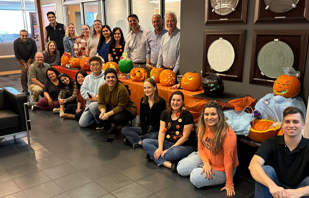 Employees pose with carved pumpkins.